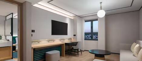 Une chambre d’hôtel moderne dotée d’une kitchenette, d’une grande fenêtre et d’un coin salon.