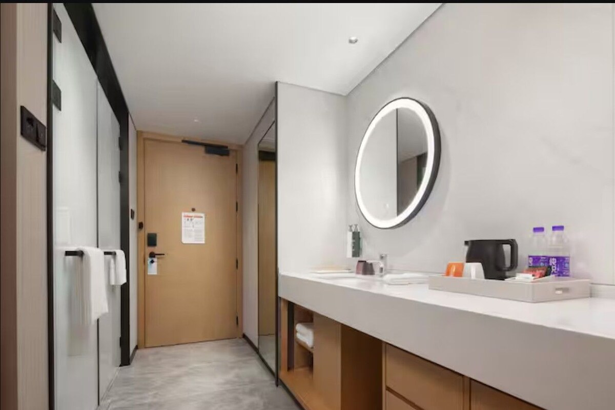 A modern bathroom with a large mirror, a sink, and a coffee maker.