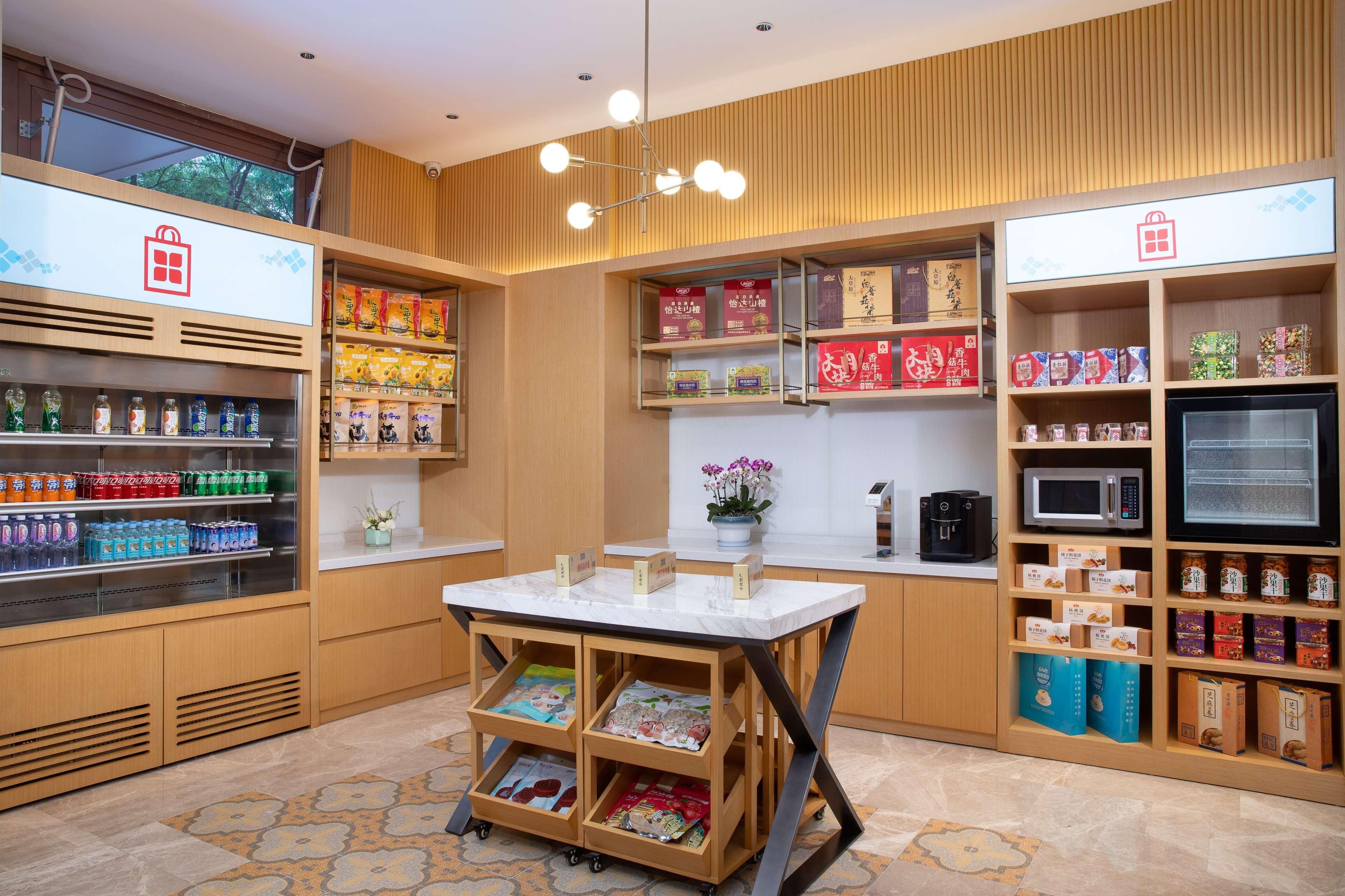 A modern retail space with a marble counter, shelves stocked with snacks and beverages, and a coffee machine.
