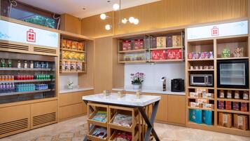 A modern retail space with a marble counter, shelves stocked with snacks and beverages, and a coffee machine.