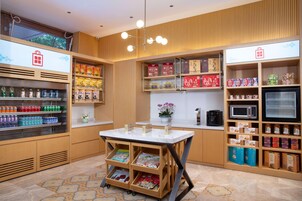 Un espacio comercial moderno con una barra de mármol, estantes llenos de aperitivos y bebidas, y una máquina de café.