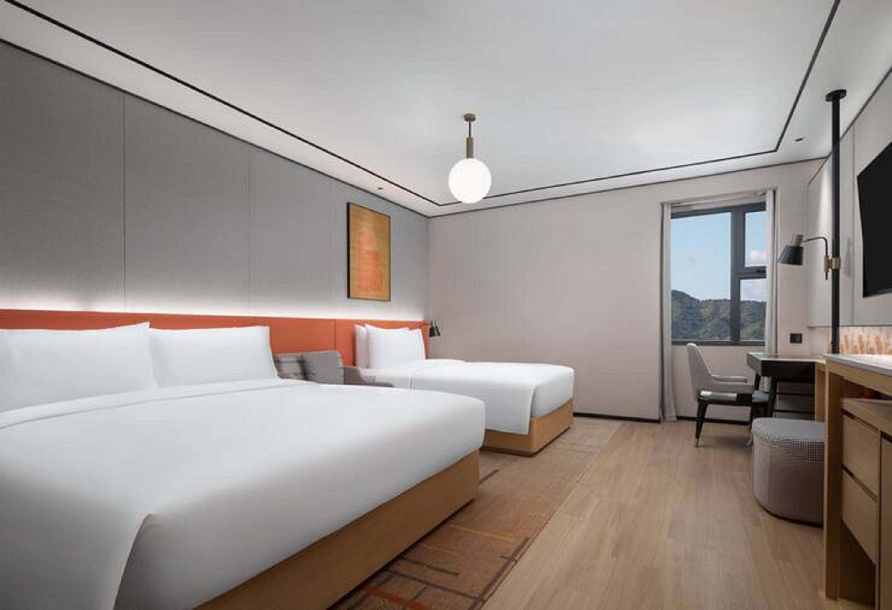 A hotel room with two beds, a desk, and a chair.