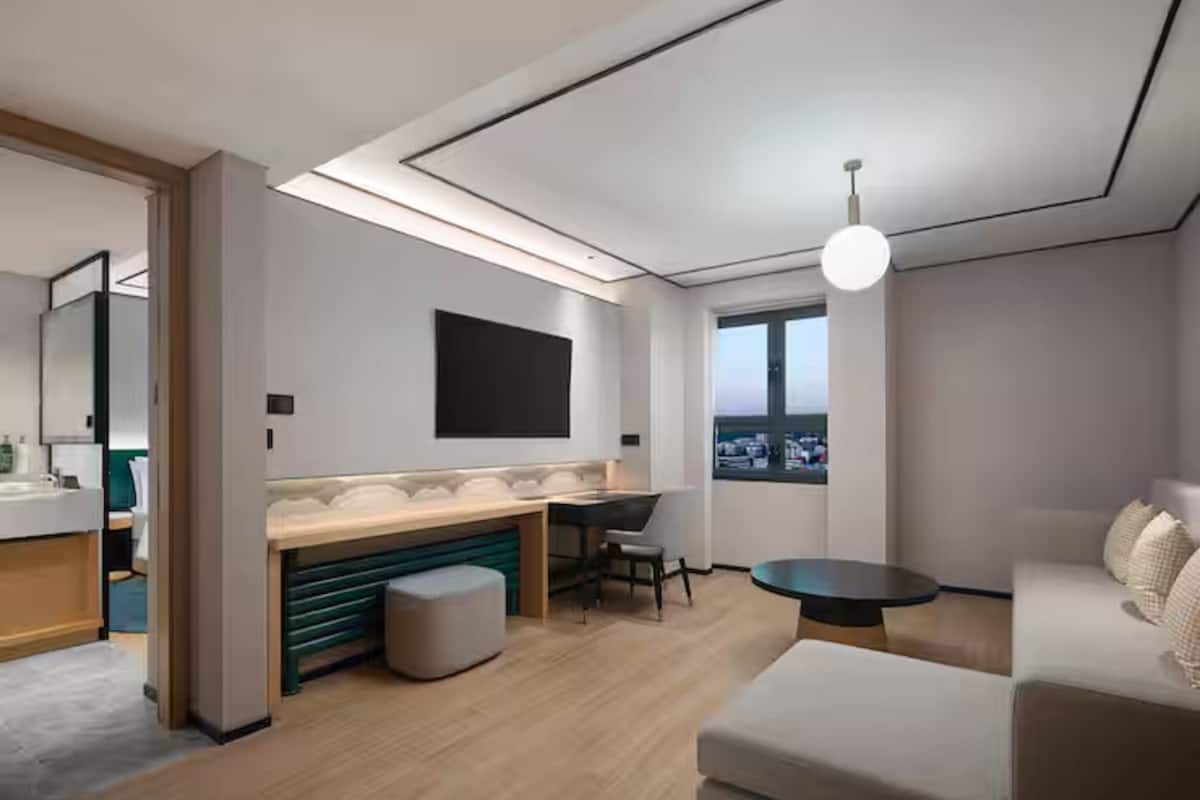 Ein modernes Hotelzimmer mit Küchenzeile, großem Fenster und einer Sitzecke.