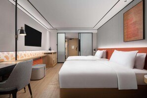 A modern hotel room with a large bed, a desk, and a chair. There is a TV mounted on the wall and a painting above the bed. - Hilton Garden Inn Chengde Mountain Resort (Chengde)