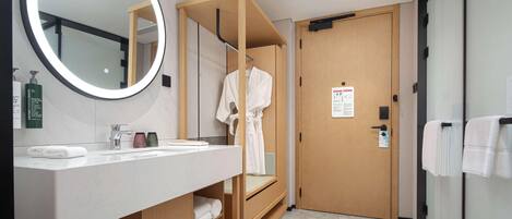 Un baño moderno con un tocador de madera, un espejo grande y una puerta de madera.