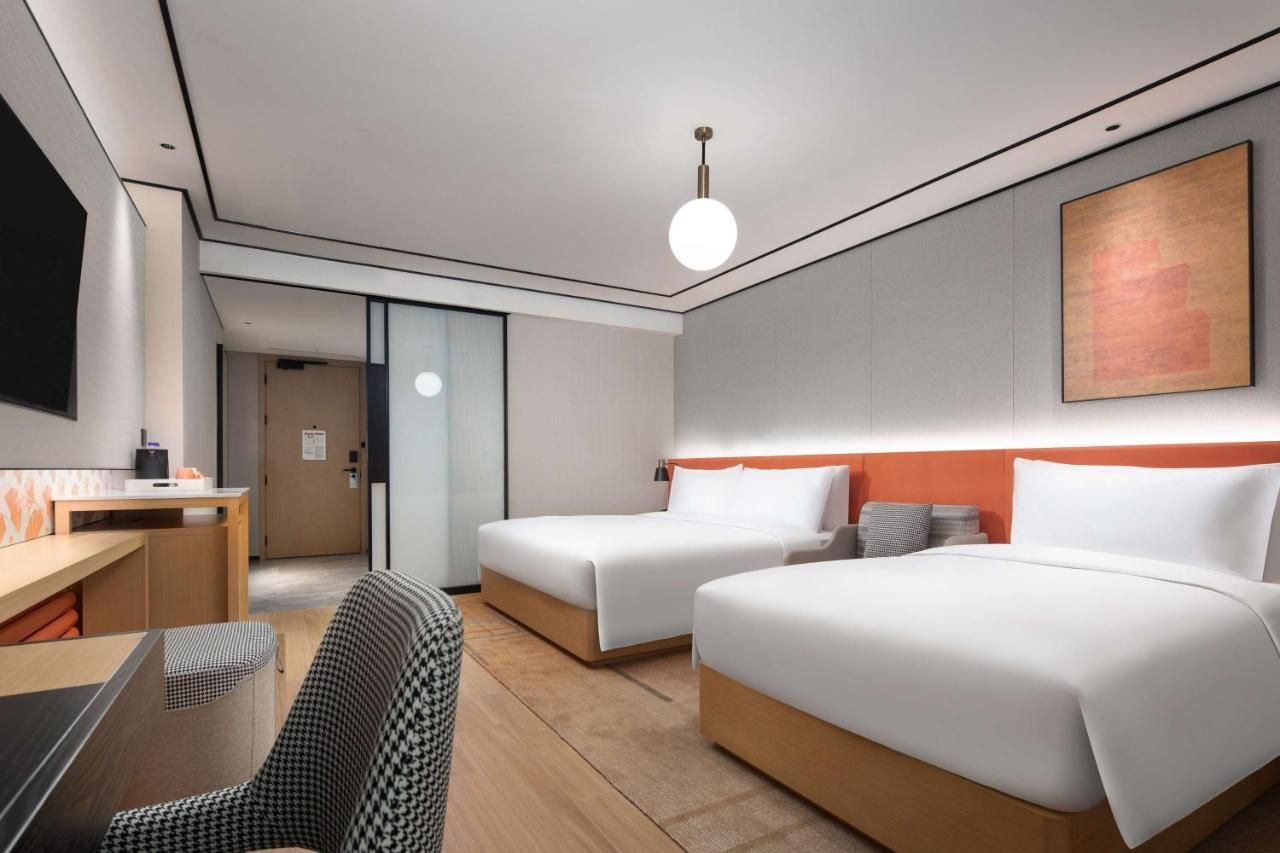 Une chambre d’hôtel moderne avec deux lits, un bureau et une chaise.
