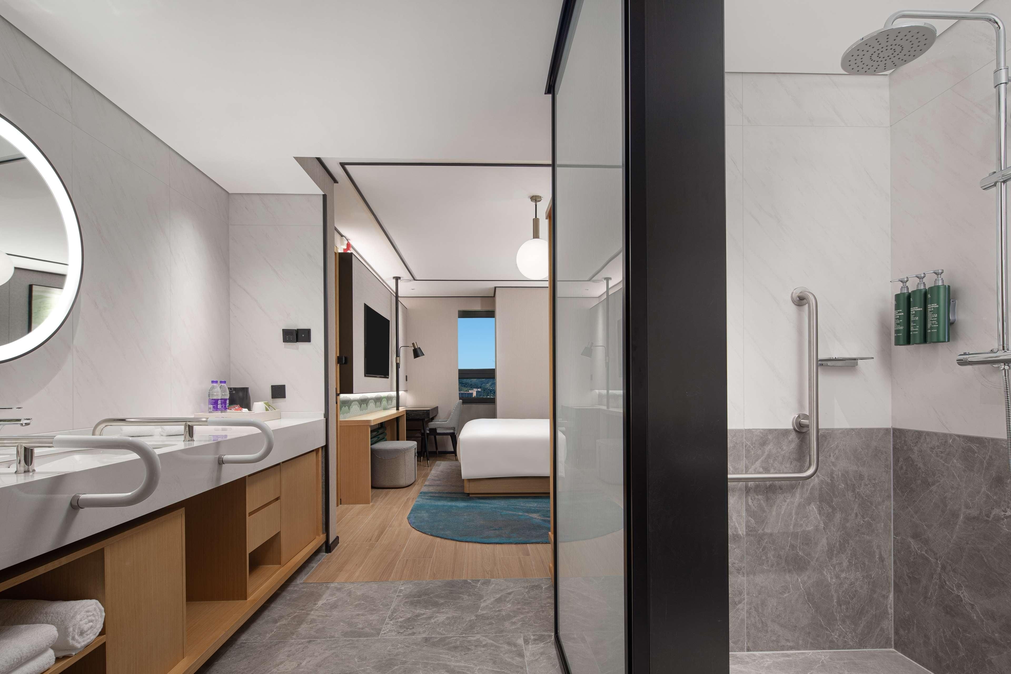 Un bagno moderno con doccia, uno specchio grande e un lavabo con mobile.