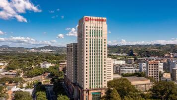 Un grand hôtel, reconnaissable à son logo rouge bien visible sur le toit, entouré de bâtiments urbains et de verdure.