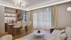 Un soggiorno moderno con un divano, un tavolino da caffè e un'area pranzo con sedie, con una cucina sullo sfondo.