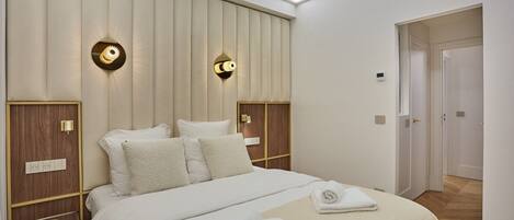 Una habitación de hotel moderna con una cama grande, dos lámparas de pared y una pared decorativa de paneles de madera.