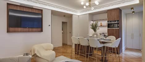 A modern living room with a sofa, a round coffee table, and a dining area with chairs and a table.