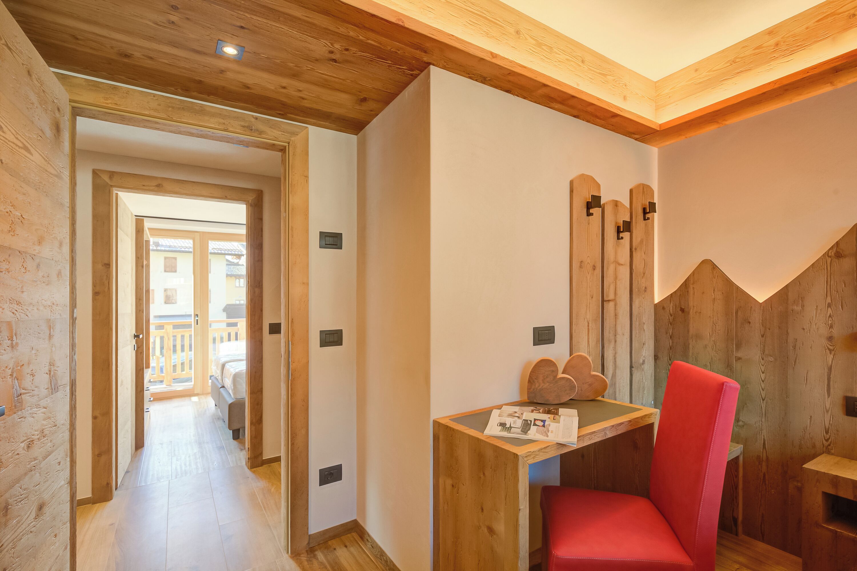 Un interior de madera con un escritorio y una silla de madera, una escalera de madera y vistas al exterior.