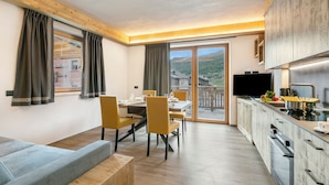 A modern kitchen with a dining area, a sofa, and a TV. - Cuore Alpino (Livigno)