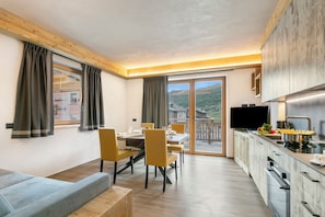 A modern kitchen with a dining area, a sofa, and a TV.