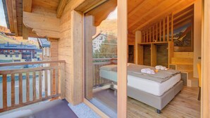 A wooden cabin with a balcony, a bed, and a painting on the wall. - Cuore Alpino (Livigno)