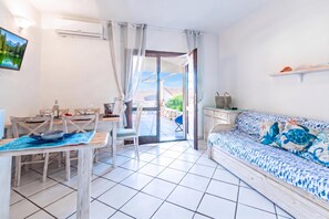A modern living room with a sofa, a dining table, and a kitchen area. - Sandy Bear Guesthouse (Palau)