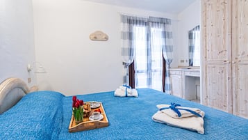 Habitación de hotel con una cama, un aparador de madera, un escritorio y una ventana con cortinas.