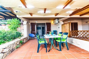 An outdoor patio with a table and chairs, a stone wall, and a wooden fence. - Sandy Bear Guesthouse (Palau)