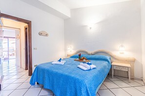 A hotel room with a bed, a wooden nightstand, a tray with breakfast items, and a view of the outside. - Sandy Bear Guesthouse (Palau)