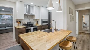 A modern kitchen with white cabinets, a wooden island, and pendant lighting. - Hines Terrace Retreat - Hot Tub & Firepit (Wisconsin Dells)