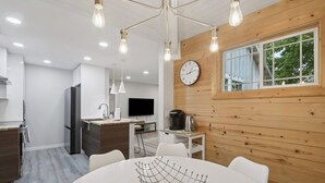 A modern kitchen with a refrigerator, sink, and a dining area with a round table and chairs. - Hines Terrace Retreat - Hot Tub & Firepit (Wisconsin Dells)