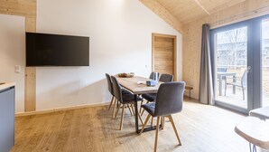A modern dining area with a wooden table, chairs, and a flat-screen TV mounted on the wall. - Ferienwohnung mit 1 Schlafzimmer & Sauna (Oberwölz)