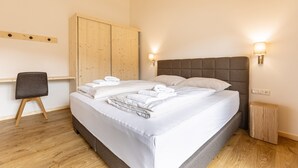 A neatly made bed with white linens and towels, a wooden wardrobe, a small bedside table, and a chair. - Ferienwohnung mit 1 Schlafzimmer & Sauna (Oberwölz)