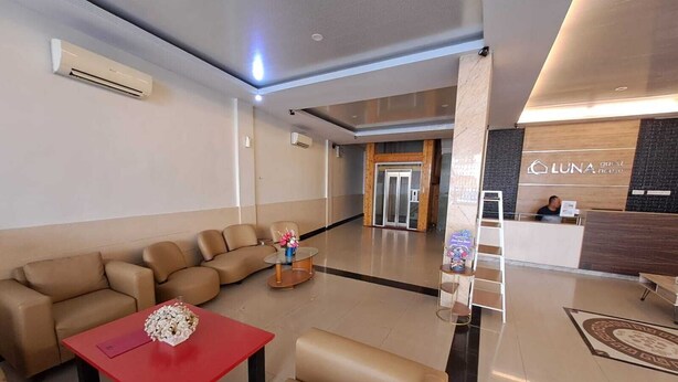 Eine Hotelhalle mit Rezeption, einer Sitzecke mit Sofas und einem Couchtisch sowie einem Empfangsbereich mit dem Schriftzug "LUNA Pension".