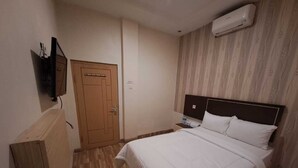 Ein Schlafzimmer mit einem Bett, einer Holztür, einem Fernseher und einer Klimaanlage.