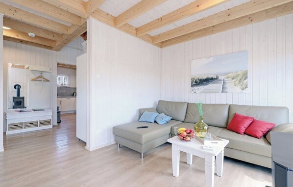 A modern living room with a sofa, a coffee table, and a kitchen in the background. - To Huus - Infrared sauna, bathtub, shower, fireplace, terrace, 2 parking spaces (Olpenitz)
