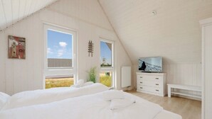 A bedroom with two beds, a TV, and a view of the outdoors.