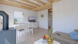 A modern living room with a TV, dining table, and a sofa.