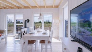 A dining area with a table set for four, a television, and a view of the outdoors.