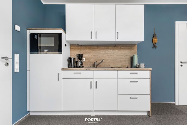 A modern kitchen with white cabinets, a built-in microwave, and a coffee maker. - Bude 3 directly on the dike in Dagebüll for 2 persons with water view (Dagebüll)
