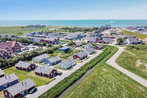 Una zona residencial costera con casas, un estrecho canal y una vista distante del mar.