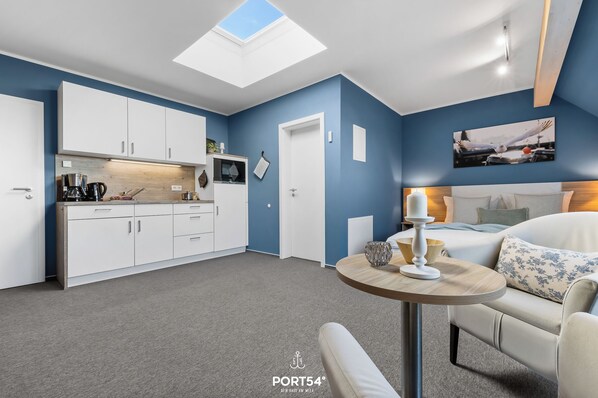 A modern room with a skylight, a bed, a small table, and a kitchenette. - Bude 5 directly on the dike in Dagebüll for 2 persons with water view (Dagebüll)