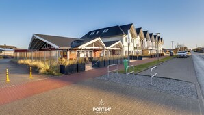 A row of modern houses with a paved walkway and a road. - Bude 10 directly on the dike in Dagebüll for 2 persons (Dagebüll)