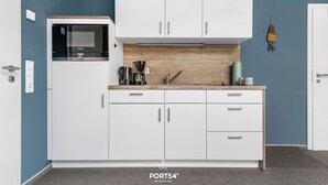 A modern kitchen with white cabinets, a built-in microwave, and a coffee maker. - Bude 10 directly on the dike in Dagebüll for 2 persons (Dagebüll)