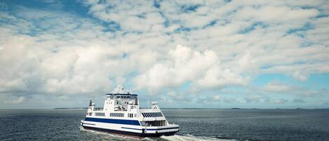 A ferry boat on a body of water with a partly cloudy sky.
