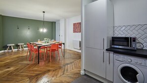 A modern kitchen with a dining area, a washing machine, and a microwave. - Superb 3 Bedroom Flat in the Center of Paris (Paris)
