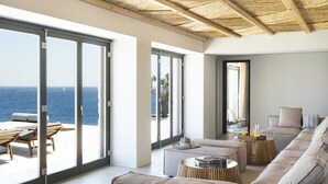 Una sala de estar moderna con amplios ventanales correderos que dan a un balcón con vistas al mar.