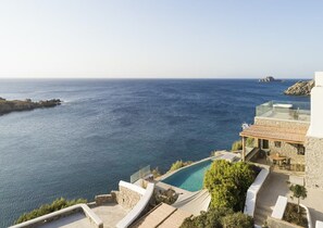 A coastal property with a clear view of the sea, a swimming pool, and a stone building with a glass roof. - Waterfront Villa With Private Pool (Mykonos)