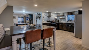 Een moderne keuken met een eethoek, met een centraal kookeiland, barstoelen en een ingebouwde oven.
