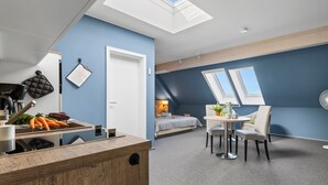 A modern kitchen with a wooden countertop, a dining area with a table and chairs, and a bedroom with a bed and skylight windows. - Bude 8 directly on the dike in Dagebüll for 2 persons with water view (Dagebüll)
