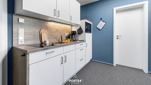 A modern kitchen with white cabinets, a wooden countertop, and a blue accent wall.