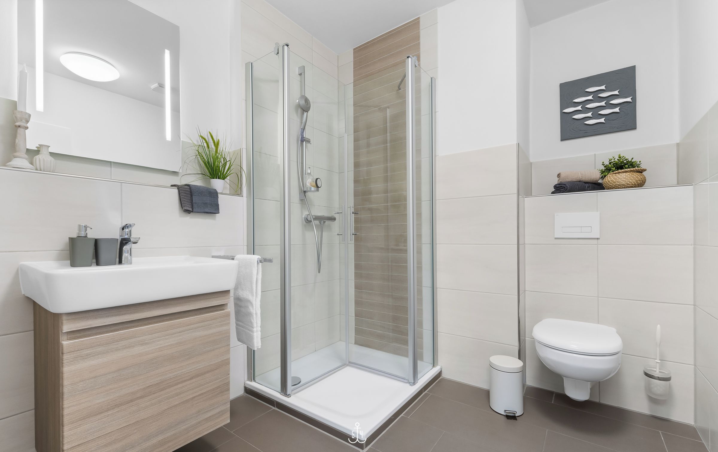 Une salle de bain moderne avec une douche à parois de verre, un lavabo blanc et des toilettes.