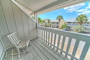 A wooden porch with a white railing and a white rocking chair. - Villa Chateau! Steps to the Beach! (Panama City Beach)