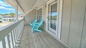 A wooden porch with a white railing, a table, and two turquoise chairs. - Villa Chateau! Steps to the Beach! (Panama City Beach)