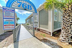 A beach entrance with a sign indicating no lifeguard on duty and warning of rip currents. - Villa Chateau! Steps to the Beach! (Panama City Beach)