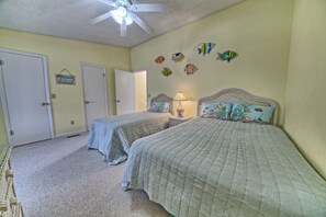 A bedroom with two beds, a ceiling fan, and a wall with fish decorations. - Villa Chateau! Steps to the Beach! (Panama City Beach)